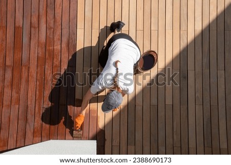 Coating with protective outdoor UV wood finish on the wooden surface of the lining boards, female worker overhead view Royalty-Free Stock Photo #2388690173