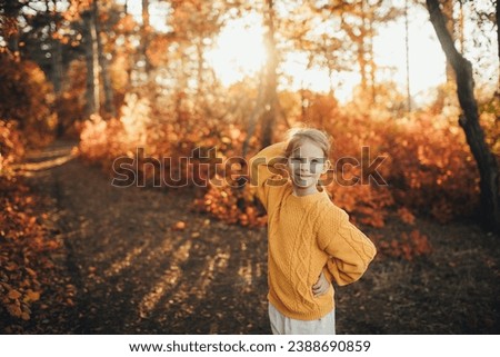 Cute 5 years old girl enjoying beautiful autumn sunset in a beautiful forest.