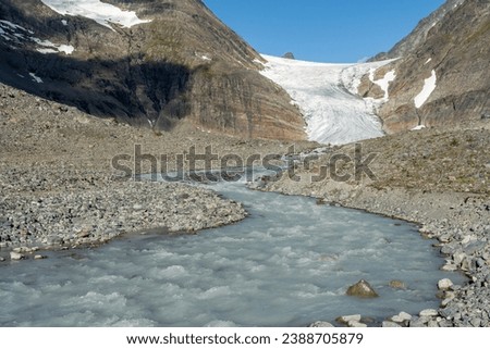 Melting  Steindalsbreen Glacier in the Steindalen Valley feds the river. Water is milky and colored because of the glacial flour.  Lyngen Alps, Northern Norway Royalty-Free Stock Photo #2388705879