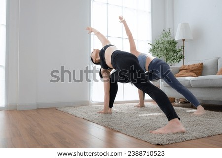 Young woman practicing yoga with instructor in house. Individual yoga class practicing in house