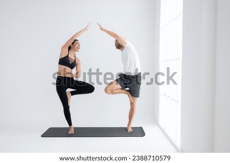 Young couple practicing yoga in a white room of studio.