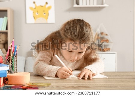Cute little girl writing in copybook at home