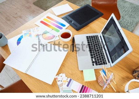 Graphic designer's workplace with laptop and color palettes in office