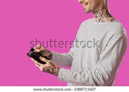 Tattooed young man with credit card and payment terminal on purple background, closeup