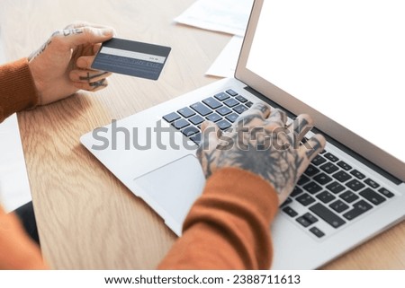 Young man with credit card using laptop at table in office, closeup
