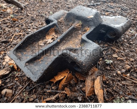 Among the fallen brown leaves lies a piece of metal track - a relic of an armored self-propelled vehicle from World War II. This juxtaposition evokes a poignant reminder of history Royalty-Free Stock Photo #2388711877