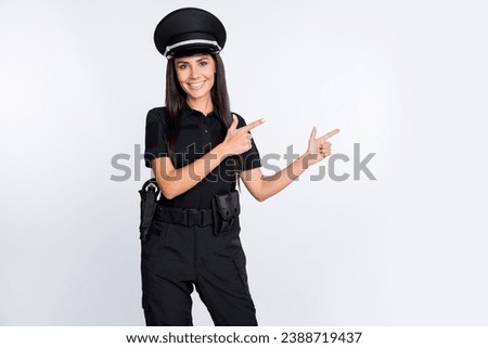 Photo of sweet cheerful young policewoman dressed black clothes headwear pointing fingers empty space isolated white color background