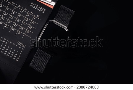 Task planning. Calendar and smart watch on a black background. Stock photo on the topic of schedules