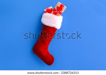 Christmas sock hanging with gift boxes on blue background