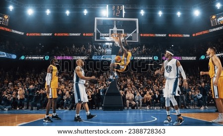 Cinematic Basketball Shot With a Talented Multiethnic Athlete Scoring a Beautiful Slam Dunk Goal. Player Celebrates by Hanging on the Hoop in Front of a Huge Crowd of Sports Fans Cheering.