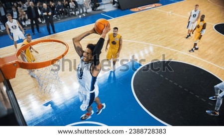 Cinematic College Basketball Tournament: Two Young Successful Diverse Teams Play a Championship Match in a Modern Arena. Excited African Player Scores a Perfect Slam Dunk with Two Hands. Royalty-Free Stock Photo #2388728383