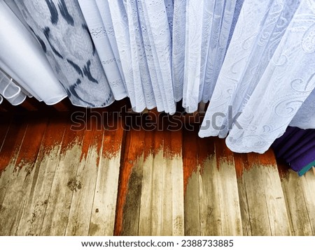 Lots of curtains or fabrics and the floor under them. Sale of curtains and fabrics in the store. Background, texture, place for text, copy space and frame