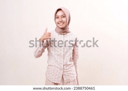 Happy young asian muslim girl standing while showing thumbs up. Isolated on white background