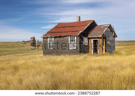 This landscape image shows one of the abandoned homes that remains in a ghost town. Most of the buildings have been razed, but a few remain, including this house and the distant grain elevator. Royalty-Free Stock Photo #2388752287