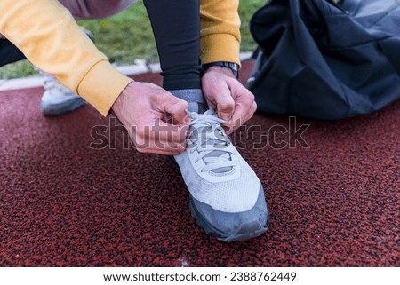 Closeup picture of a man tying his shoelaces, focus on running shoes and hands tying the shoelaces