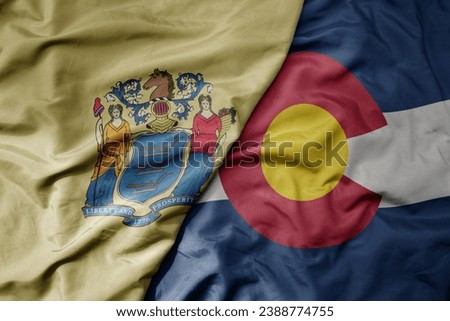 big waving colorful national flag of colorado state and flag of new jersey state . macro