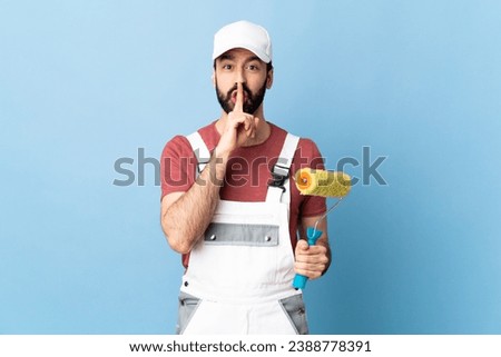 Adult painter man over isolated blue background showing a sign of silence gesture putting finger in mouth
