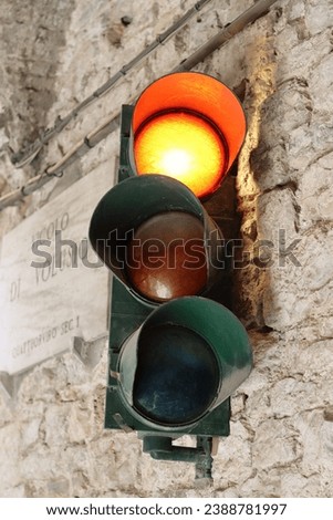 Traffic light attached to a stone wall, shining red