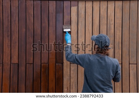 Handy woman improving house hardwood cladding with wood stain application. Do it yourself concept.  Royalty-Free Stock Photo #2388792433