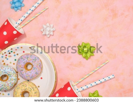 Colorful celebration design. Flat lay composition, copy space for text. Donuts with glaze and colored sprinkles, cocktails in bright cups with straws, festive bows.