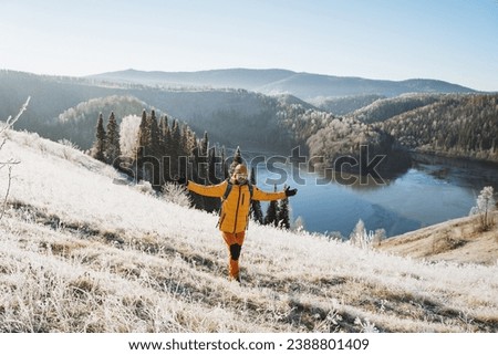 A man travels in the mountains against the background of a mountain lake in winter, trekking in the cold season, sports equipment on a hike, the first snow in nature. High quality photo