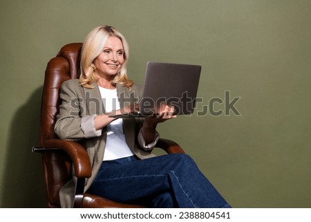 Photo of mature woman ecommerce seller trader sitting boss armchair using laptop amazon discounts isolated on khaki color background