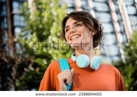 Photo of cheerful pretty girl dressed orange t-shirt eyewear backpack walking university outdoors urban town park