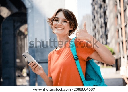 Photo of cheerful satisfied girl walking in street park cityscape showing thumb up 5g connection network nice sunny weather outdoors