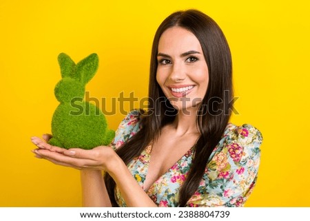 Portrait of positive cute woman with long hairstyle wear stylish dress palms presenting green rabbit isolated on yellow color background