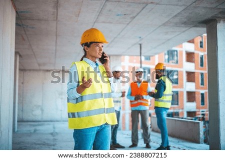 Shot of a young engineer using a smartphone in an industrial place of work. Architect is using mobile phone on construction site. She is focused on her work. Construction woman closing deal