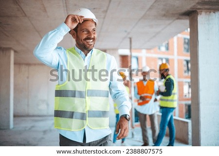 Portrait of satisfied and confident engineer with helmet and news on building site. Close-up portrait of professional architect in hard hat looking away. Attractive engineer at work on construction 
