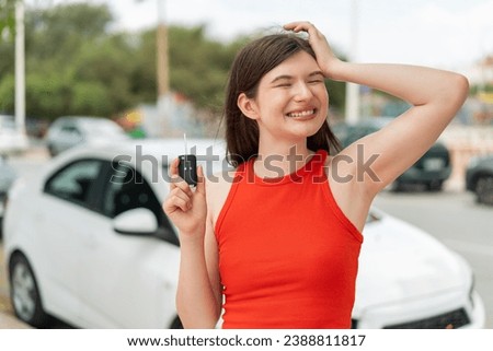 Young pretty Ukrainian woman holding car keys at outdoors has realized something and intending the solution