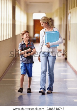 Everyone has that favorite teacher...A teacher and young boy walking together down the corridor. Royalty-Free Stock Photo #2388818743
