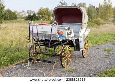 A beautiful empty carriage stands without a horse on a rural road. The elegant white carriage stands empty. Concept of an old fashioned carriage driven by a horse.