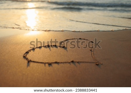 A heart is drawn on the sand on the beach at sunset. Romantic sunset on the beach. Heart shape. Heart symbol. Love.