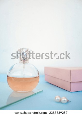 Minimalist composition with women's bottle of perfume on blue background. Floral Fragrance and spring mockup. Perfumery and beauty concept. Front view.