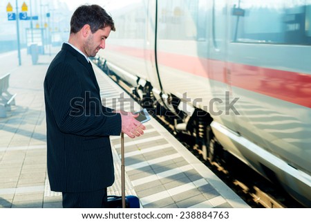 businessman in suit on railroad station waiting for train