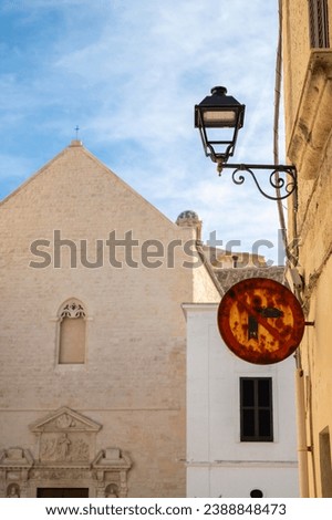 Fragment of the facade of a historic church building, a lantern on the facade, a rusty road sign, a sunny day