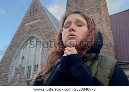 Portrait of young sad praying woman or religious teenager girl on Catholic Church background. 