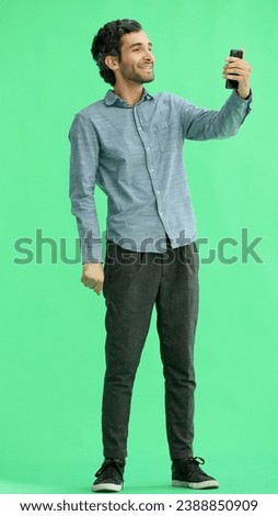 young man in full growth. isolated on green background taking selfie