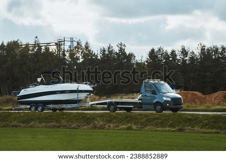 Luxury Boat Journey on the Road. Light-duty truck is hauling a Luxury Motor Boat at Sunset. Close-up of a medium-sized new yacht is being delivered to the customer. Royalty-Free Stock Photo #2388852889