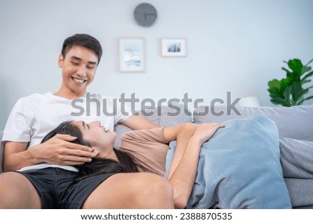 Happy relaxed young family couple homeowners or renters lying on big cozy sofa, enjoying carefree leisure weekend time, celebrating moving into new contemporary apartment, tenancy concept.
