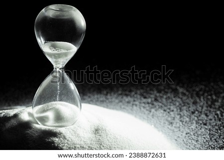 Hourglass add more sand of time on white sand over black background. White hourglass show more time Deadline extended time management hope concept hour glass, life clock passing by