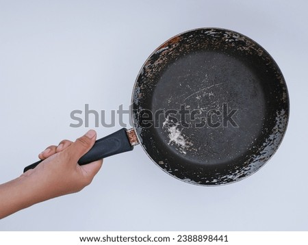 hand holding old used metal frying pan, isolated on white Royalty-Free Stock Photo #2388898441