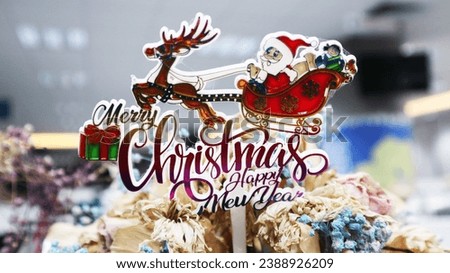 an acrylic sticker that says "Merry Christmas and a Happy New Year" with a picture of Santa Claus and a reindeer flying on a sleigh.