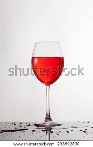 Red wine glass  with drops falls on the floor in a white background