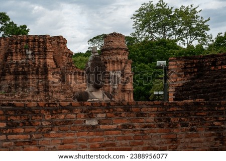 Ruined Buddha statue and ancient building at Wat Mahathat, (Temple of the Great Relic), a Buddhist temple in Ayutthaya Thailand.