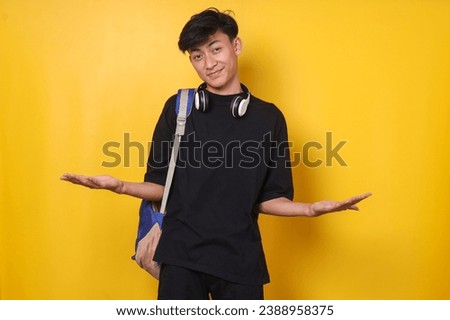 Asian student wearing backpack presenting advertisement with hands open