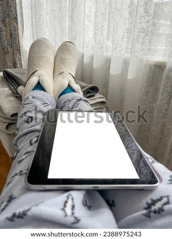 casual woman relaxing on sofa and using digital tablet with white blank or empty screen in living room. tablet computer or touch screen pad on nap of woman sitting by window in a sunny day at home