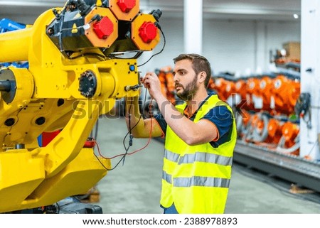 Mechanical engineer inspecting and fixing a mechanical arm on an industrial production line